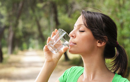 Junge Frau, die aus einem Glas Wasser trinkt 
