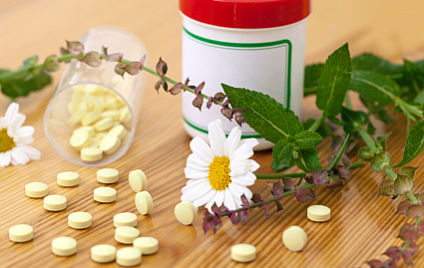 Dose mit Tabletten und daneben Kräuter